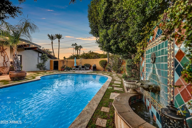 pool at dusk featuring a patio