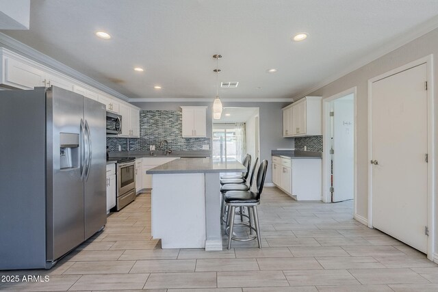 7135 W Flower St, Phoenix, AZ 85033 - kitchen with stainless steel appliances, crown molding, backsplash, a kitchen bar, and white cabinetry