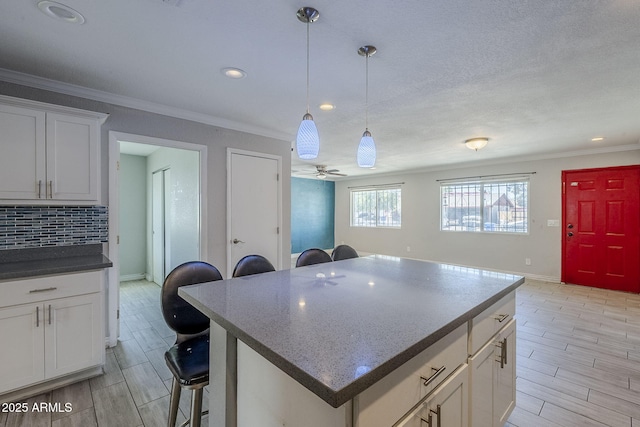7135 W Flower St, Phoenix, AZ 85033 - kitchen featuring a kitchen bar, ornamental molding, baseboards, decorative backsplash, and a center island