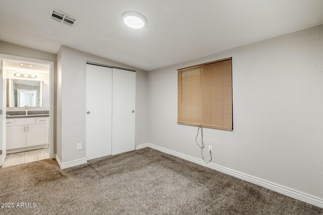 7135 W Flower St, Phoenix, AZ 85033 - unfurnished bedroom with carpet, lofted ceiling, a closet, ensuite bath, and baseboards