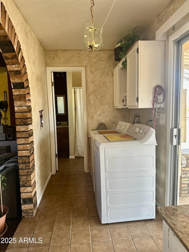 washroom featuring cabinet space, light tile patterned floors, a notable chandelier, and independent washer and dryer