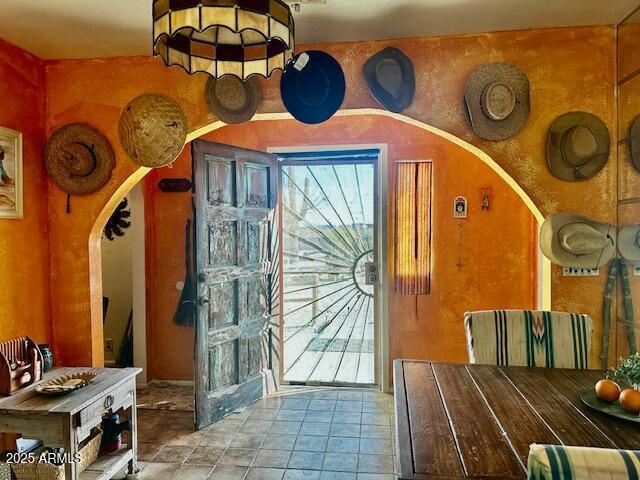 doorway with arched walkways, plenty of natural light, and tile patterned flooring