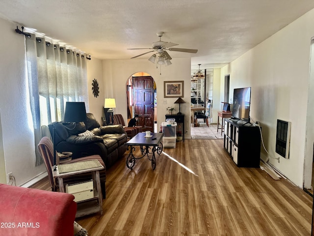 living room with heating unit, ceiling fan, arched walkways, and wood finished floors