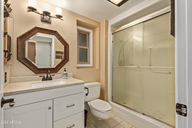 bathroom with tile patterned floors, vanity, an enclosed shower, and toilet