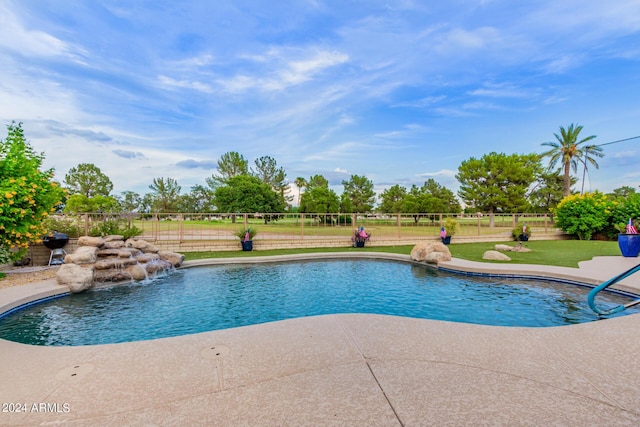 view of swimming pool with pool water feature, a patio area, and a yard