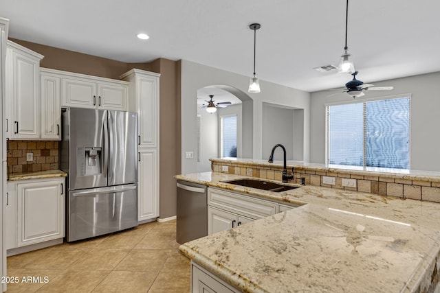 kitchen with sink, light stone counters, hanging light fixtures, appliances with stainless steel finishes, and white cabinets