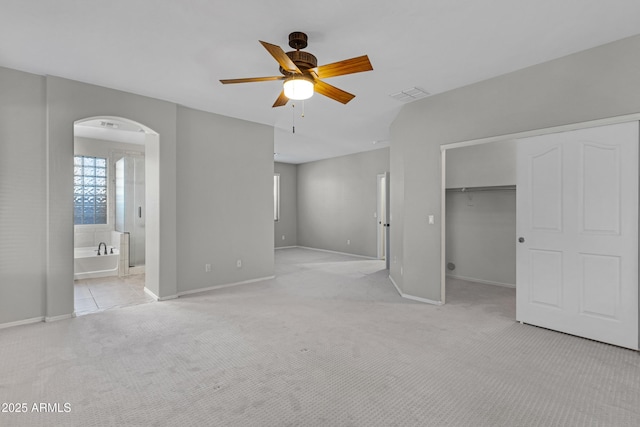 interior space with light colored carpet, ensuite bathroom, a closet, and a walk in closet