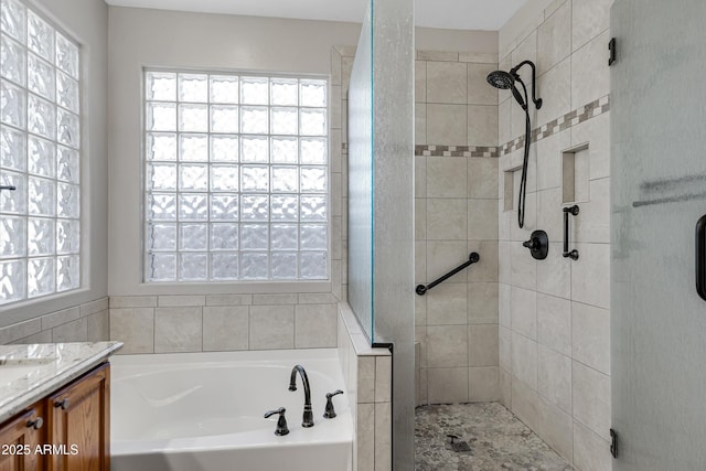 bathroom featuring shower with separate bathtub, a healthy amount of sunlight, and vanity