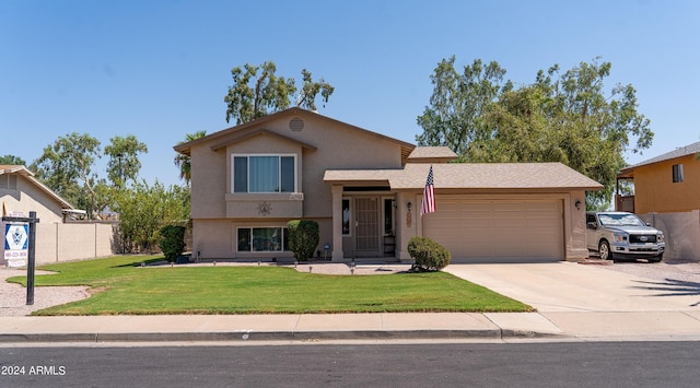 tri-level home featuring driveway, an attached garage, fence, a front lawn, and stucco siding