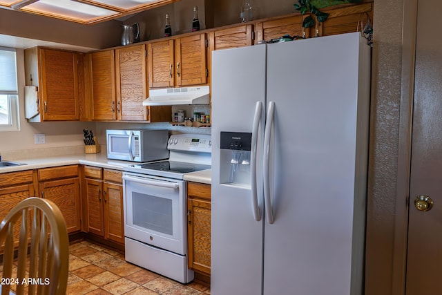 kitchen featuring light countertops, white appliances, brown cabinets, and under cabinet range hood