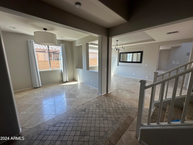 empty room featuring a notable chandelier and light tile patterned floors