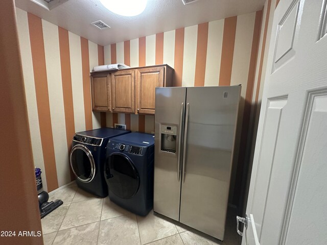 washroom featuring separate washer and dryer, cabinets, and light tile patterned floors