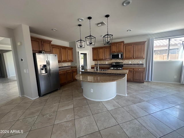 kitchen featuring stainless steel appliances, tasteful backsplash, sink, a chandelier, and a center island with sink