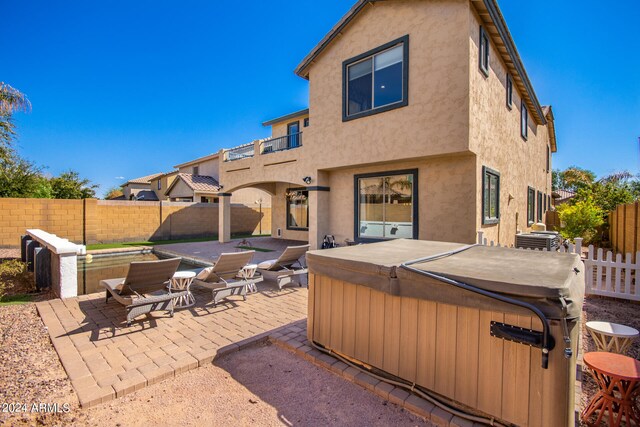 rear view of house with central AC, a patio area, and a hot tub