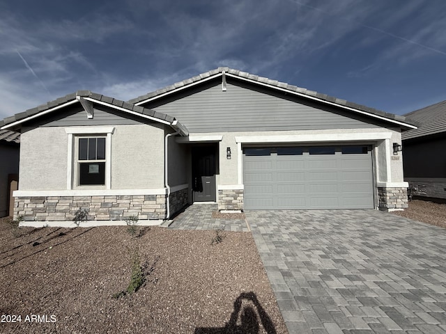 view of front facade featuring stone siding, stucco siding, driveway, and a garage