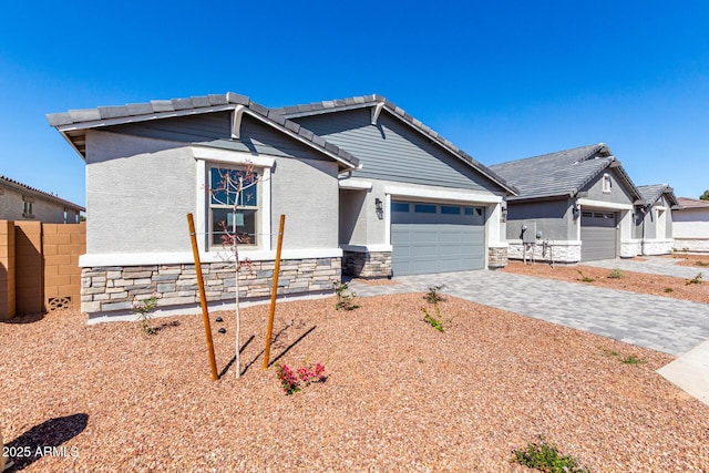 view of front of home featuring stone siding, a tiled roof, decorative driveway, and an attached garage