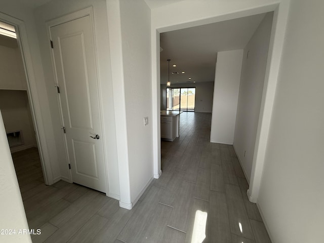 corridor with baseboards and wood finished floors