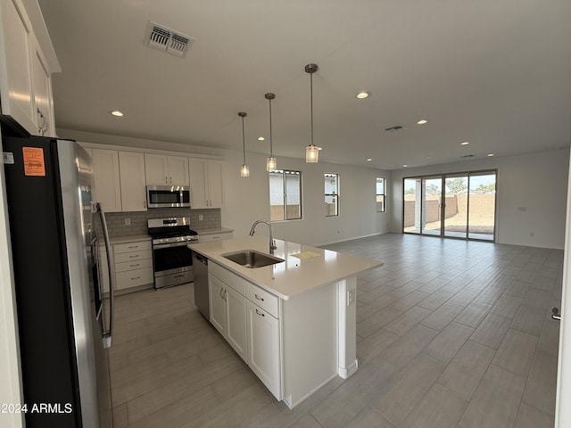 kitchen featuring light countertops, a sink, backsplash, appliances with stainless steel finishes, and visible vents