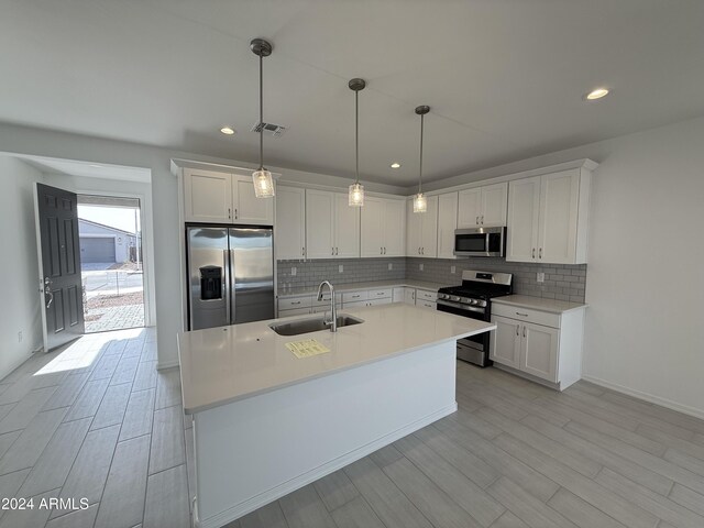 kitchen with decorative backsplash, white cabinets, visible vents, stainless steel appliances, and a sink