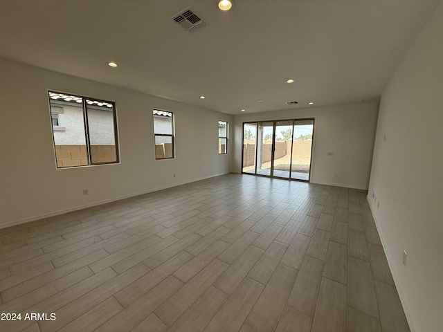 spare room featuring wood finished floors, recessed lighting, baseboards, and visible vents