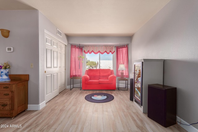 living area with wood finished floors, visible vents, and baseboards