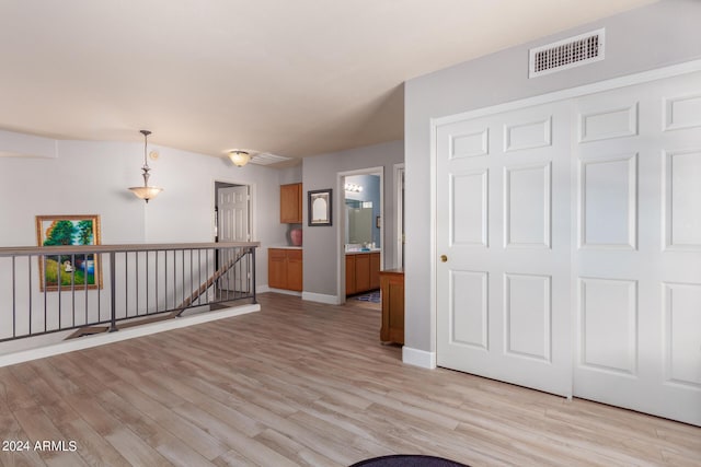 interior space with baseboards, an upstairs landing, visible vents, and light wood-type flooring