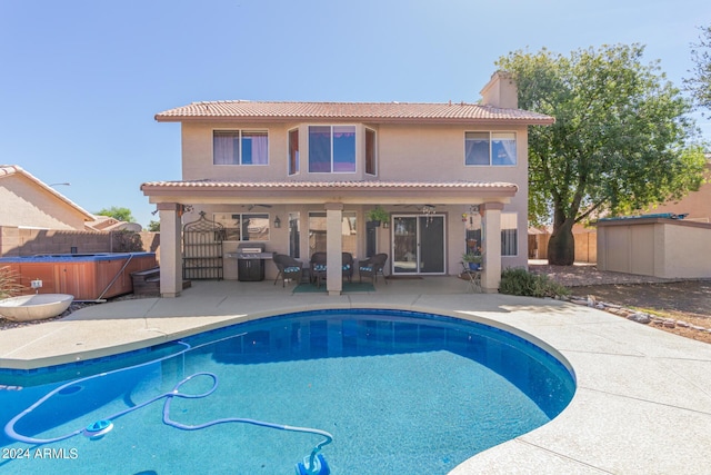 rear view of property featuring a patio, a fenced backyard, a chimney, and a hot tub