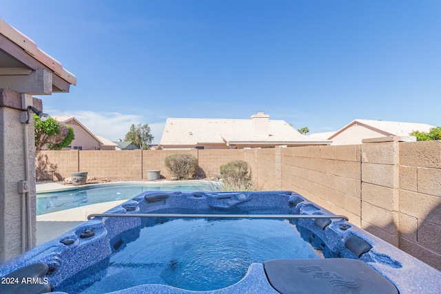 view of swimming pool featuring a fenced backyard, a fenced in pool, and a hot tub