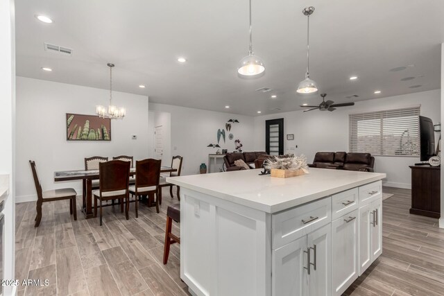 935 Calle Azul, Wickenburg, AZ 85390 - kitchen with white cabinetry, open floor plan, light countertops, hanging light fixtures, and wood tiled floor