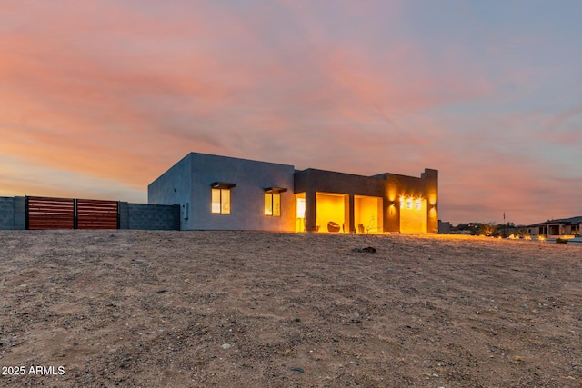 back of house at dusk featuring fence