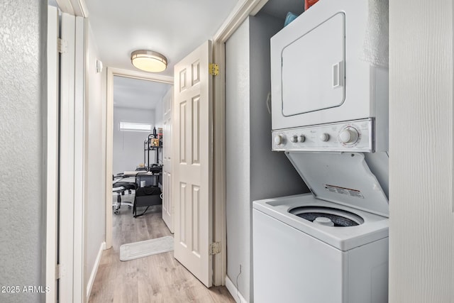 laundry room with stacked washing maching and dryer and light hardwood / wood-style flooring