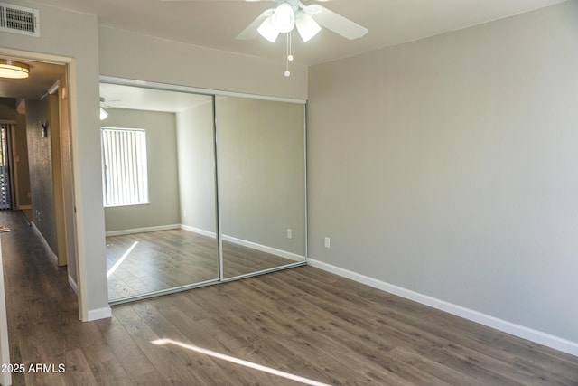 unfurnished bedroom featuring dark hardwood / wood-style flooring, ceiling fan, and a closet