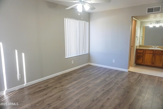 unfurnished bedroom with hardwood / wood-style floors, ensuite bath, ceiling fan, and sink