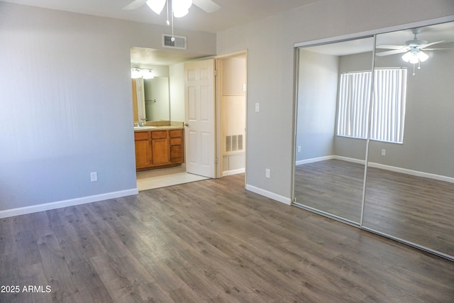 unfurnished bedroom with hardwood / wood-style floors, sink, ceiling fan, connected bathroom, and a closet