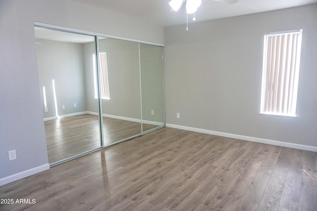 unfurnished bedroom featuring ceiling fan, wood-type flooring, and a closet