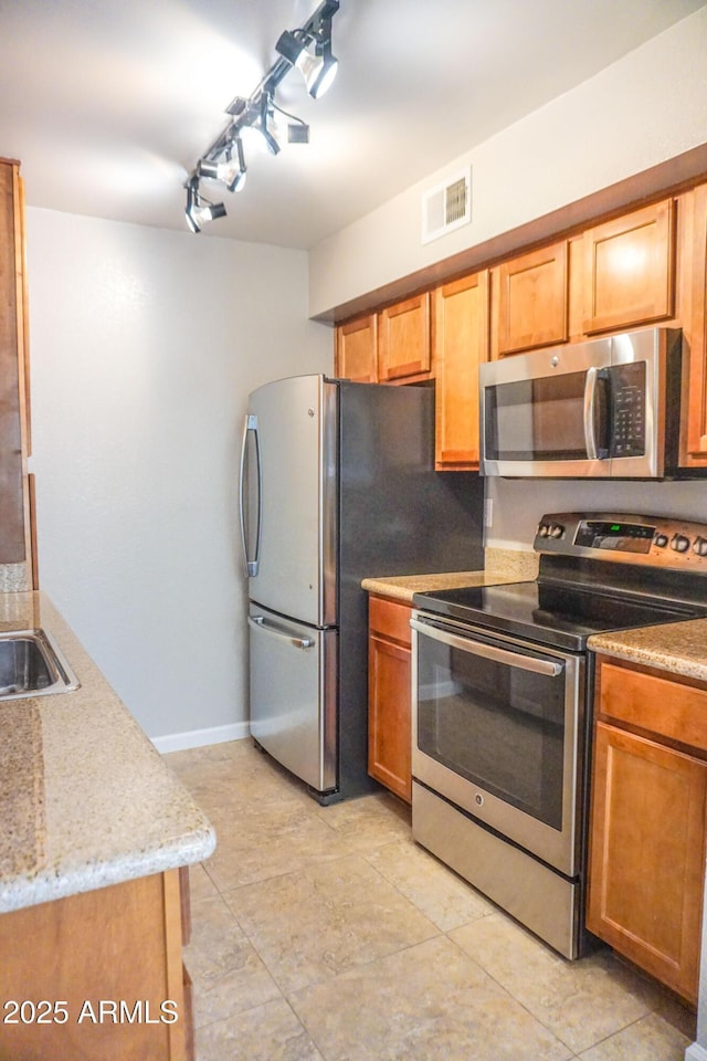 kitchen with light stone countertops, appliances with stainless steel finishes, and sink