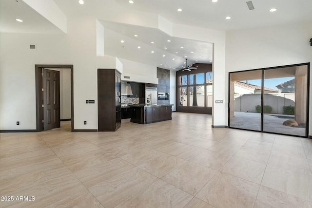 unfurnished living room with ceiling fan, a high ceiling, and sink