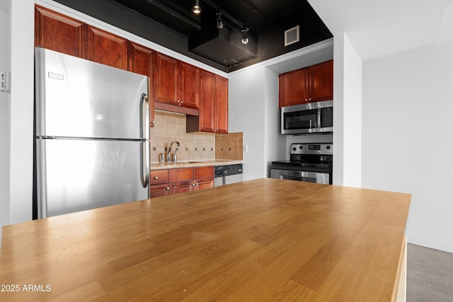 kitchen with backsplash, wooden counters, visible vents, appliances with stainless steel finishes, and a sink