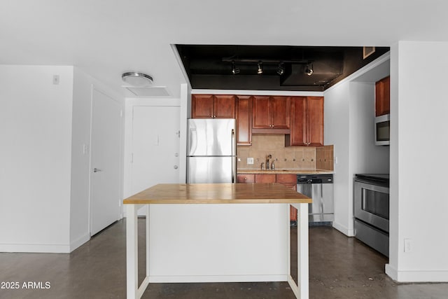 kitchen with tasteful backsplash, concrete flooring, baseboards, and stainless steel appliances