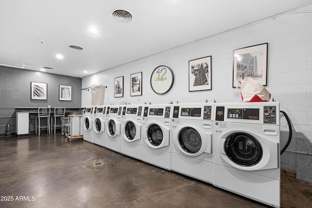 shared laundry area featuring visible vents, concrete block wall, washer and dryer, and recessed lighting