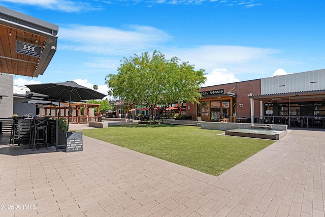 view of property's community featuring outdoor dry bar, a patio area, and a lawn