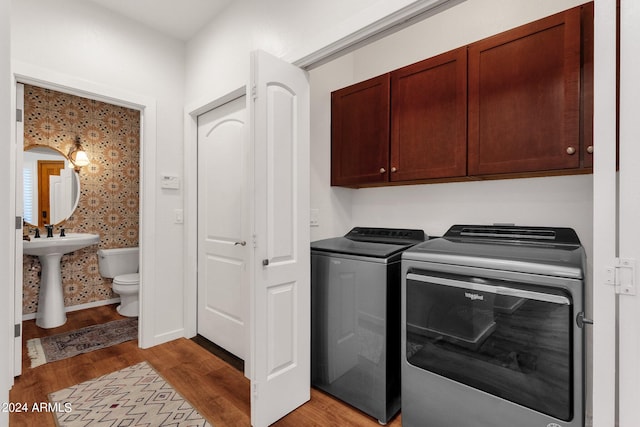 clothes washing area with light hardwood / wood-style flooring, cabinets, and separate washer and dryer