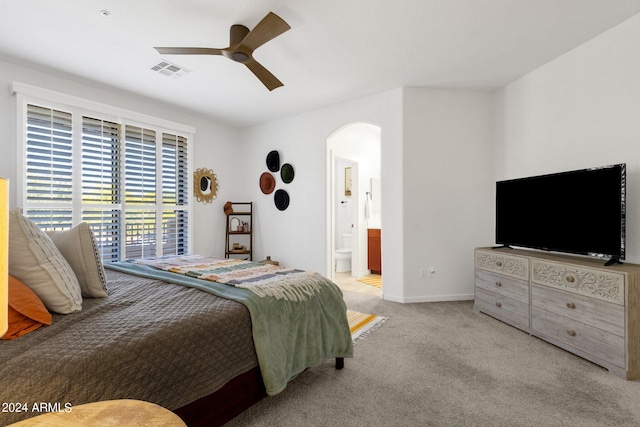 bedroom with light carpet, connected bathroom, and ceiling fan