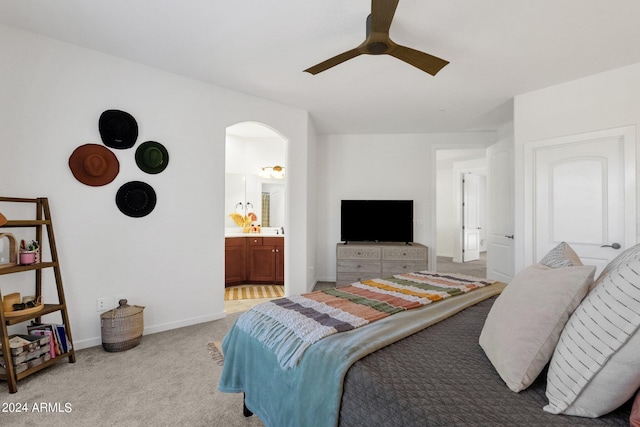 bedroom with light colored carpet, ensuite bath, and ceiling fan