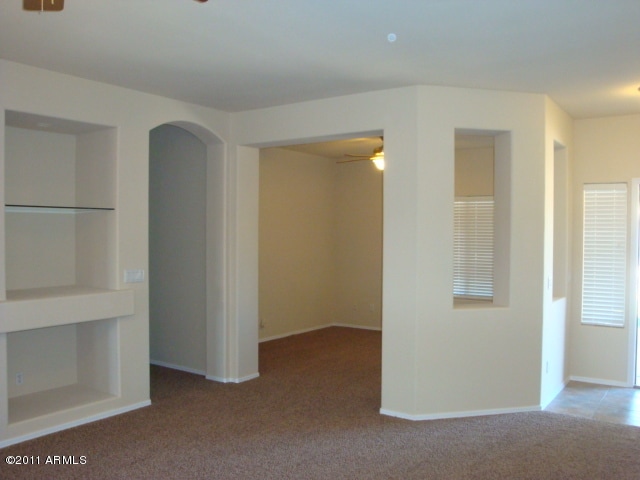 20985 N 81st Dr, Peoria, AZ 85382 - empty room featuring ceiling fan, carpet, arched walkways, and baseboards