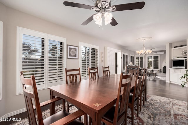 dining room with ceiling fan with notable chandelier and dark hardwood / wood-style flooring