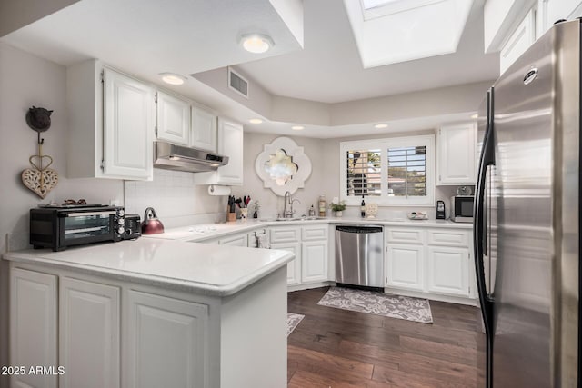 kitchen featuring appliances with stainless steel finishes, kitchen peninsula, sink, and white cabinets