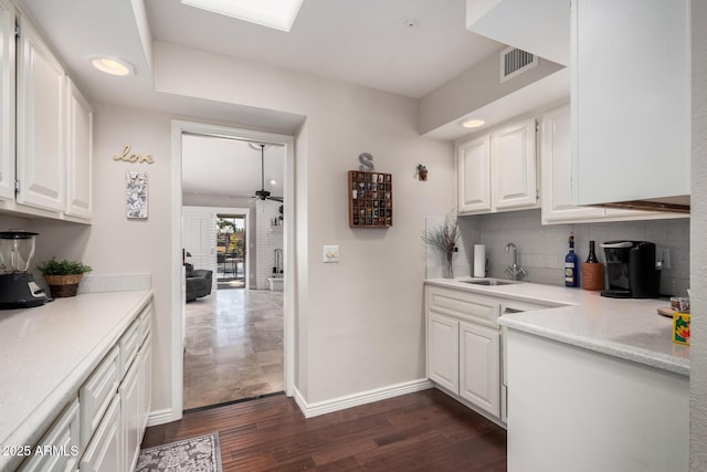 kitchen with sink, ceiling fan, white cabinetry, backsplash, and dark hardwood / wood-style floors