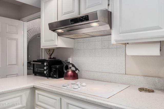 kitchen with white cabinetry, white stovetop, and extractor fan