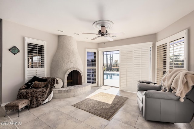 tiled living room featuring ceiling fan and a large fireplace